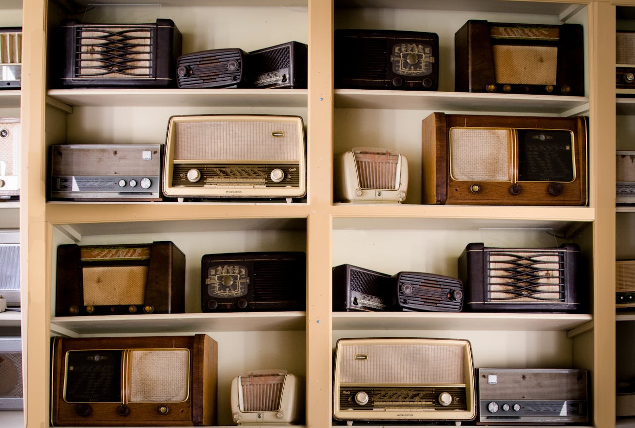 our-mission A curated collection of vintage radios displayed on shelves in an antique store, showcasing retro designs.